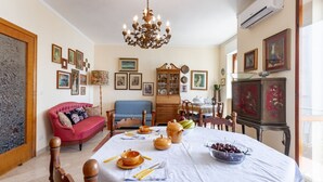 A dining area with a table set for a meal, a chandelier, and a red sofa. - GuestHost - Bella Vista Apartment with balcony SEA VIEW (Otranto)