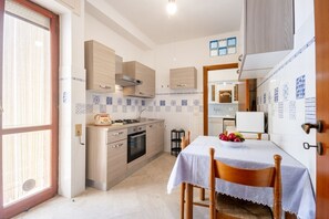 A kitchen with wooden cabinets, a stove, and a dining table with chairs.