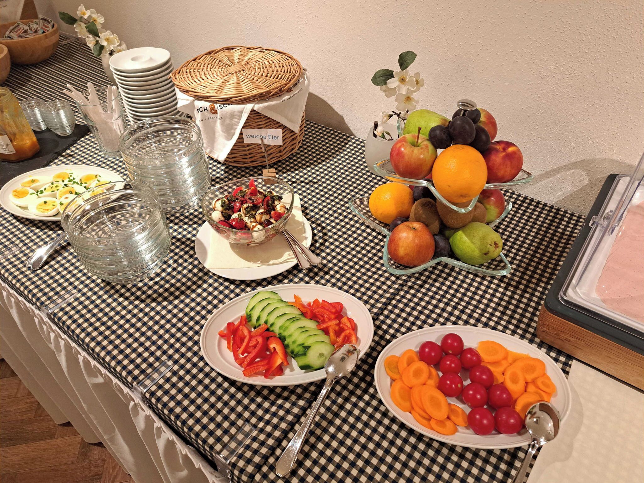 A buffet table with various food items, including fruits, vegetables, and a salad.