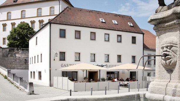 A public square with a fountain, a building with a sign reading "GASTHAUS," and a statue. - Hotelgasthof Bayerischer Hof (Sulzbach-Rosenberg)