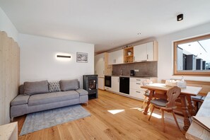 A modern kitchen with wooden cabinets, a dining table with chairs, a built-in oven, and a large window.