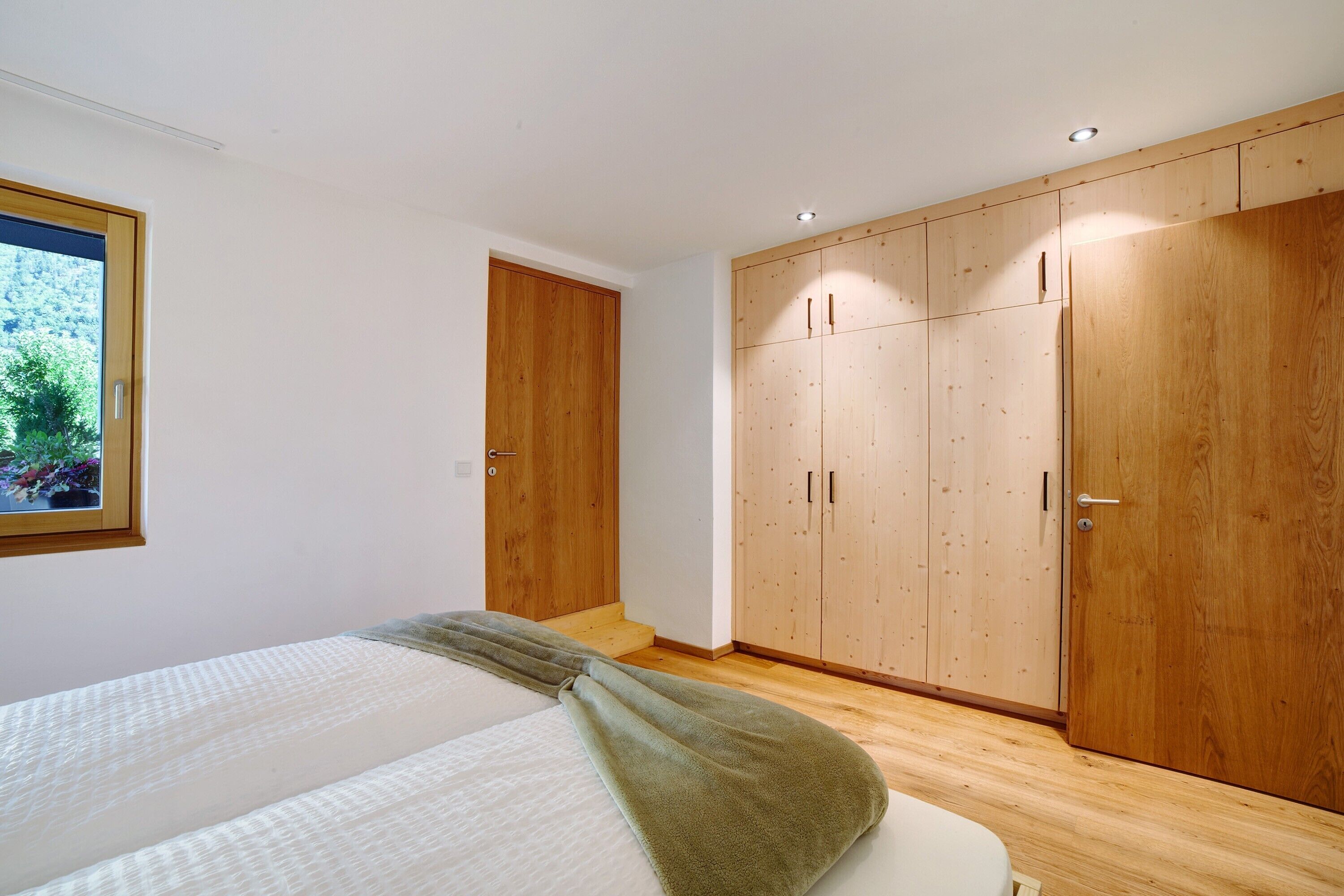 Une chambre à coucher avec un lit, une armoire en bois et une fenêtre donnant sur un paysage verdoyant.