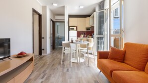 Un salon moderne avec un canapé, un téléviseur et un coin repas comprenant des chaises et une table.