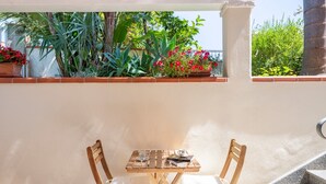 A small outdoor seating area with a table and chairs, surrounded by plants and a view of the outdoors. - Holiday Home "Loft Pina" with Wi-Fi, Garden & Terrace (Arbatax)