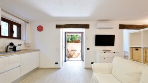 A modern kitchen with a dining area, a sofa, and a television. - Holiday Home "Loft Pina" with Wi-Fi, Garden & Terrace (Arbatax)