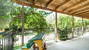 A covered outdoor area with a bench, wooden beams, and a metal fence.