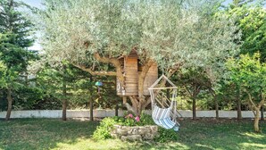 Ein Baumhaus mit einer Hängematte und Blumen in einem Garten.