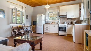 Eine Küche mit Holzausstattung, einem Kühlschrank, einem Backofen und einem Essbereich mit Stühlen und einem Tisch.