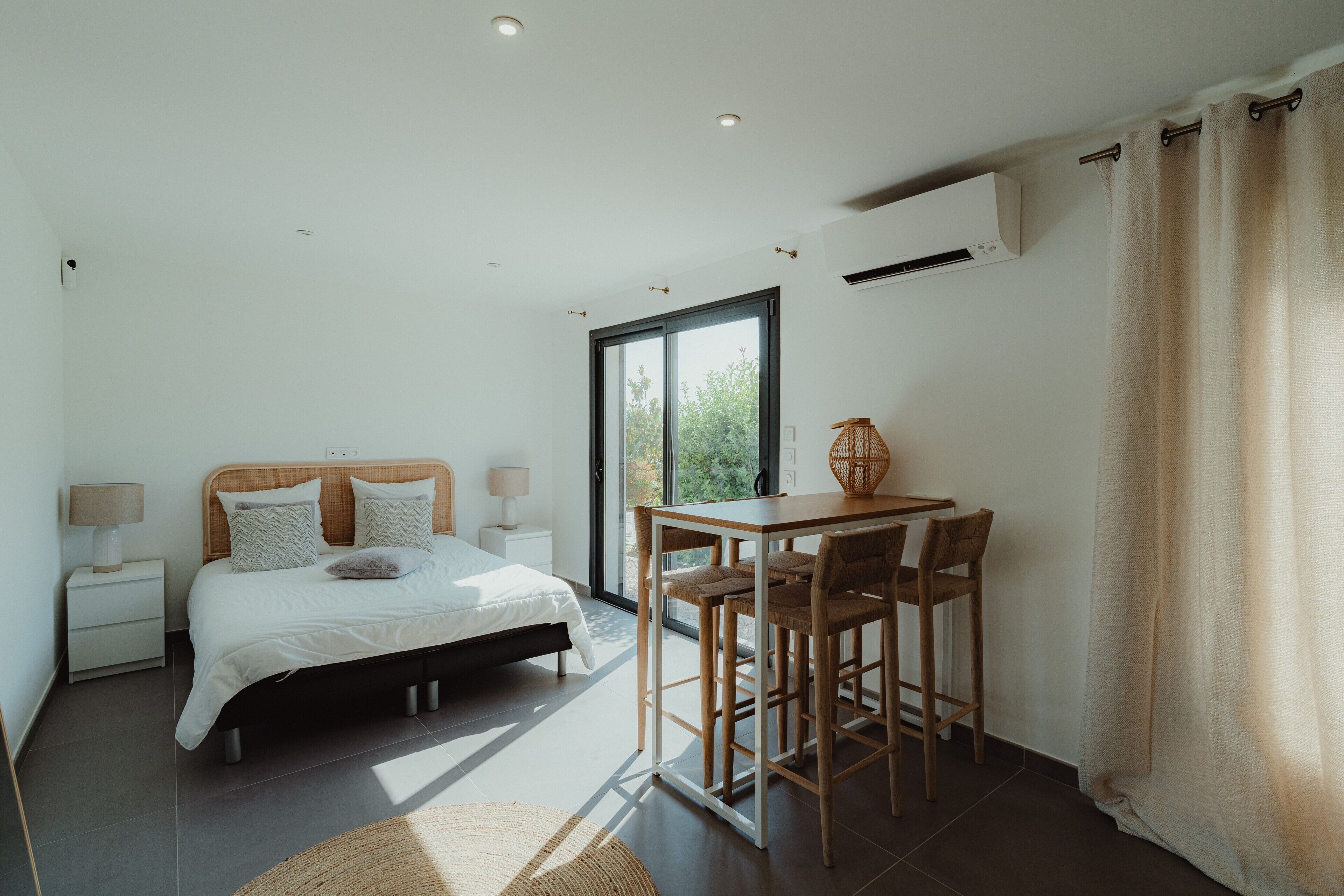 Een slaapkamer met een bed, nachtkastje, lamp en een raam.