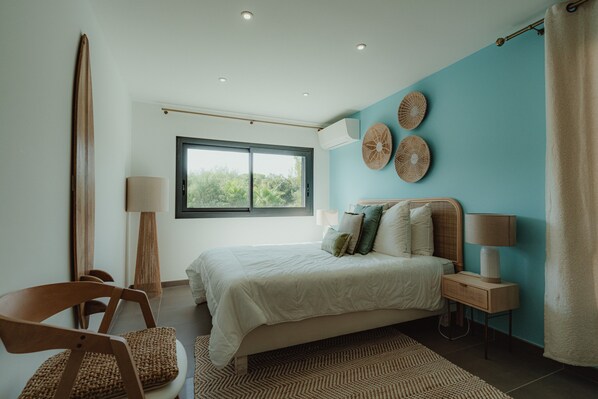 A bedroom with a bed, a window, a lamp, and a chair.