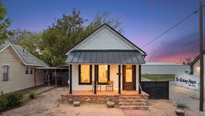 Una casita de una sola planta con un porche, cimientos de ladrillo y un letrero que dice 'The Wishing House' en Waco, Texas.