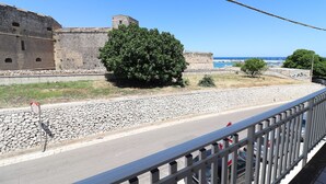 A stone wall, a tree, and a road with cars. - Casa Paola Otranto Apartment with Sea View, Balcony and Air Conditioning (otranto)