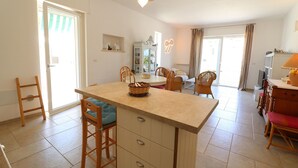 A spacious kitchen with a central island, wooden chairs, and a dining table. - Casa Paola Otranto Apartment with Sea View, Balcony and Air Conditioning (otranto)