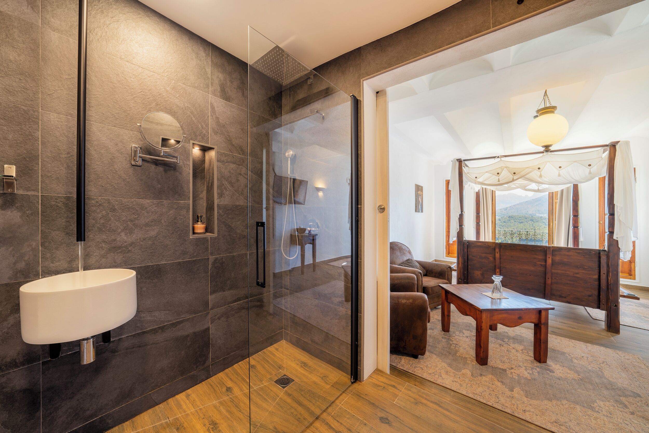 A modern bathroom with a glass-enclosed shower, a white sink, and a wooden floor.