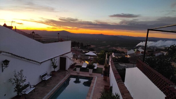 A rooftop pool area with a view of the sunset over mountains.