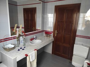 A bathroom with a white marble sink, wooden doors, and a red and white tiled backsplash.