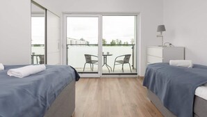 Ein Hotelzimmer mit zwei Betten, einem Balkon mit Tisch und Stühlen sowie einer Lampe.