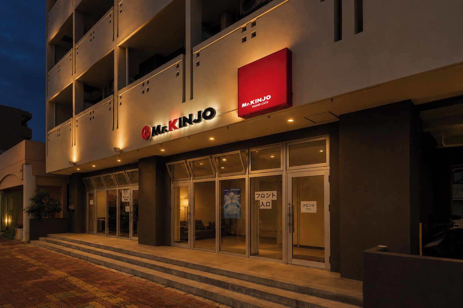 A building with a sign for 'Mr. Kinjo Grand Cats' and a storefront with glass doors.