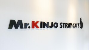 Eine Wand mit der Aufschrift "Mr. Kinjo Stray Cats" in schwarzen und roten Buchstaben.