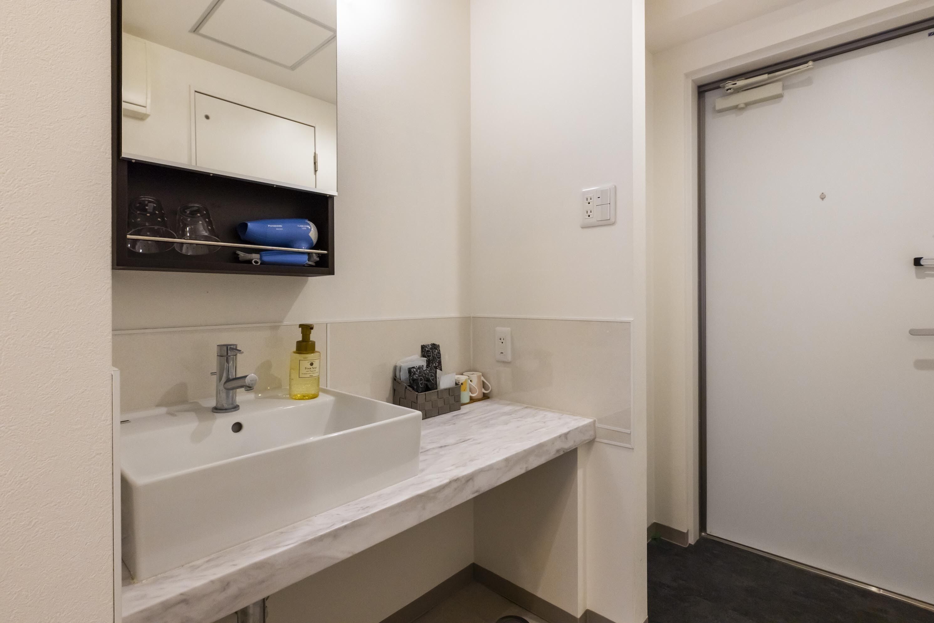 A bathroom with a white sink, a mirror, and a door.