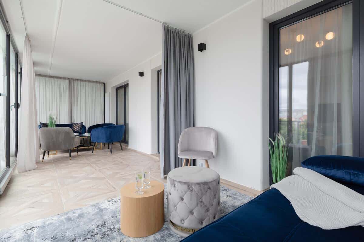 A modern living room with a sofa, ottoman, and a dining area with chairs and a table.