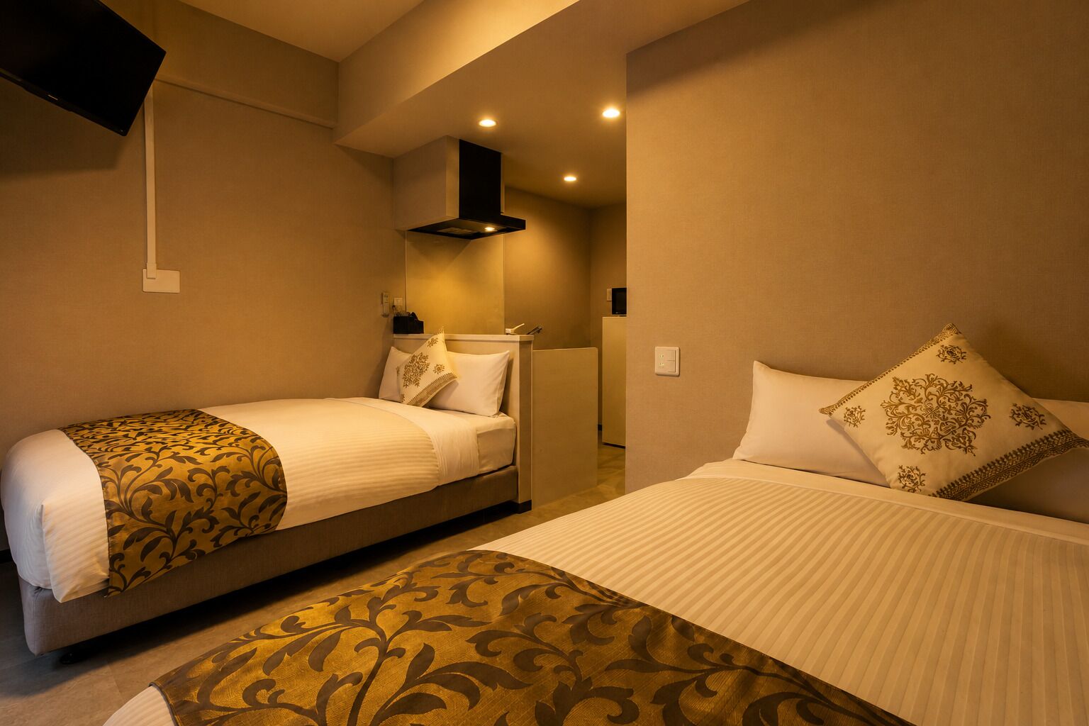 Une chambre d’hôtel avec deux lits, un téléviseur à écran plat fixé au mur et un design moderne.