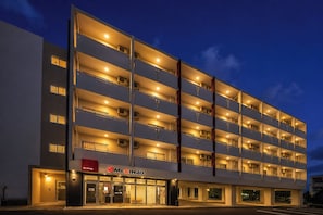A multi-story hotel with a modern design, featuring balconies on each floor and a visible entrance with a sign. - Mr.KINJO En ISHIGAKI (Ishigaki)