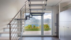 Un interior moderno con una escalera que lleva a un balcón con vistas a un paisaje montañoso.