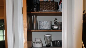 Una cocina con una puerta blanca, estantes con utensilios de cocina, una licuadora y una cafetera.