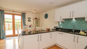 A modern kitchen with white cabinets, a black countertop, and a green tiled backsplash. - Kestrel, 19 Dartmouth Green (Totnes)