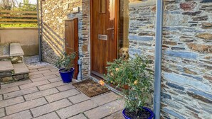 A stone building with a wooden door and a potted plant in front. - Kestrel, 19 Dartmouth Green (Totnes)