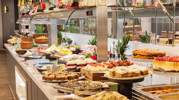 Buffet com diversos tipos de comida e uma vitrine de vidro.