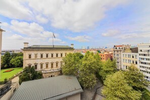 Un edificio histórico con techo verde, rodeado de árboles y otros inmuebles.