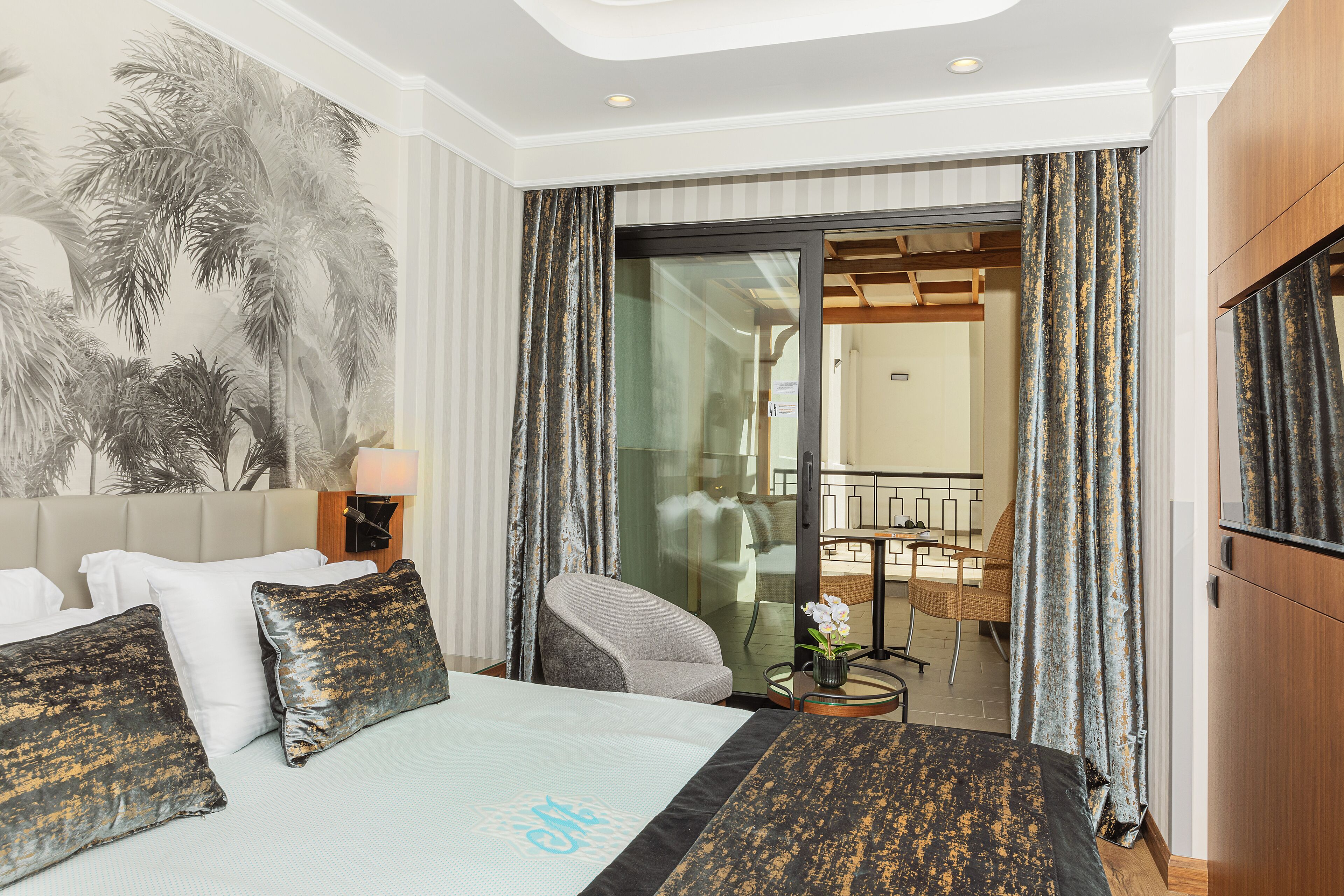Habitació d'hotel amb llit, una cadira, escriptori i un balcó amb cortines.