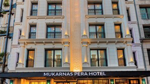 Um hotel com fachada clássica, várias varandas e uma entrada bem iluminada.