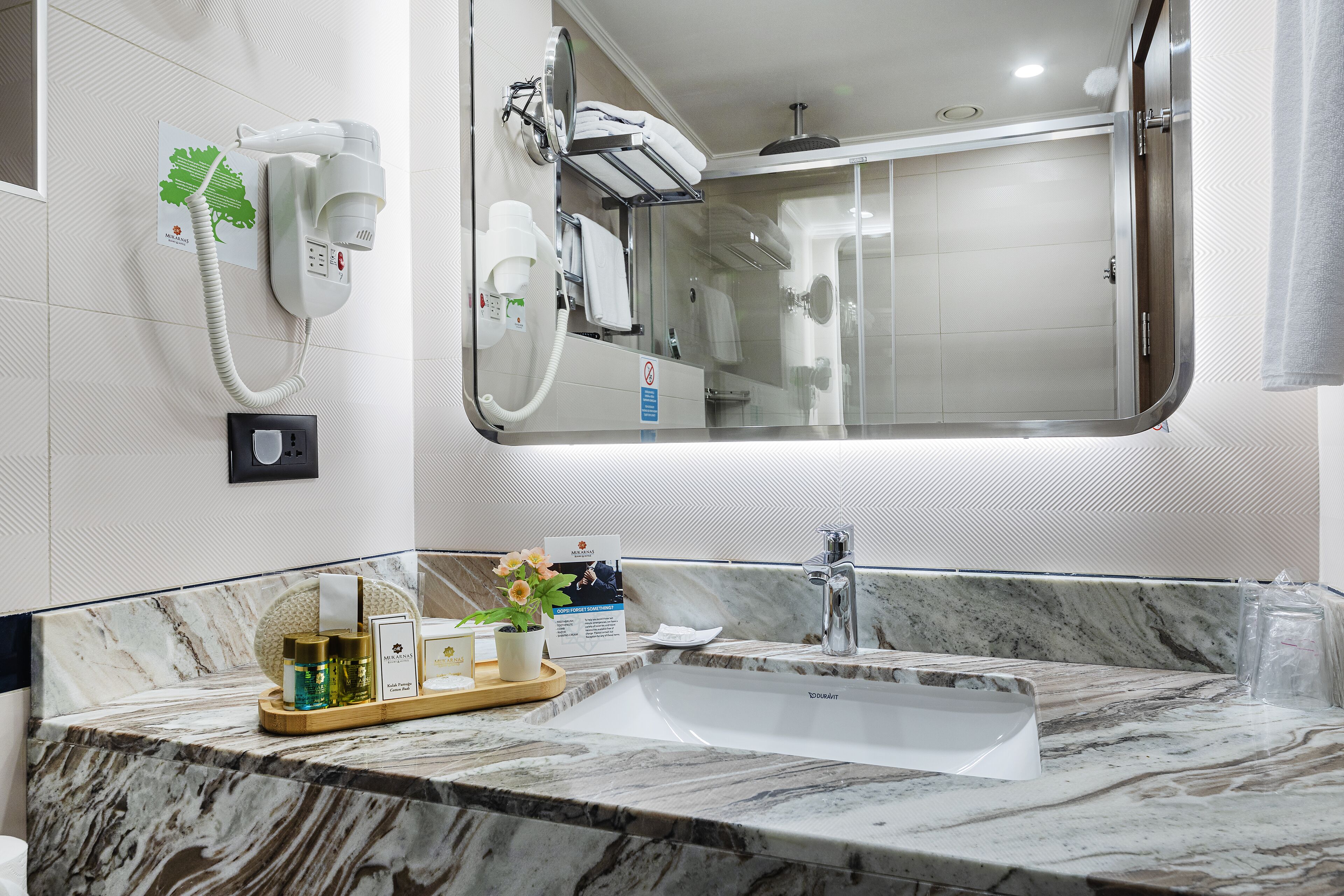 Une salle de bain avec un lavabo en marbre, un miroir, un sèche-cheveux et un porte-serviettes.