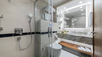 A modern bathroom with a glass-enclosed shower, a toilet, and a sink with a marble countertop.