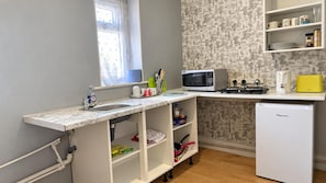 A compact kitchen with a sink, microwave, toaster, and refrigerator.