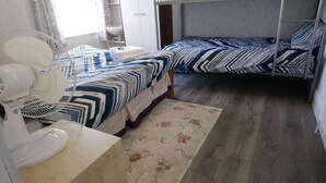 A bedroom with a bed, a fan, a small table, and a nightstand. - Renovated 4-bed Home, Sleeps 9 With Parking & Spa (Blackpool)