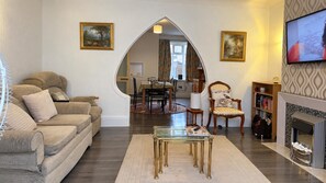 Una sala de estar con sofá, mesa de centro, chimenea y televisor.