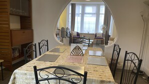 A dining area with a table set for four, surrounded by chairs. There is a mirror on the wall reflecting the room. - Renovated 4-bed Home, Sleeps 9 With Parking & Spa (Blackpool)