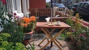 An outdoor patio area with a table and chairs, surrounded by potted plants and a gravel ground. - Renovated 4-bed Home, Sleeps 9 With Parking & Spa (Blackpool)