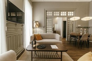 A living room with a sofa, a coffee table, and a dining area with chairs and a table.