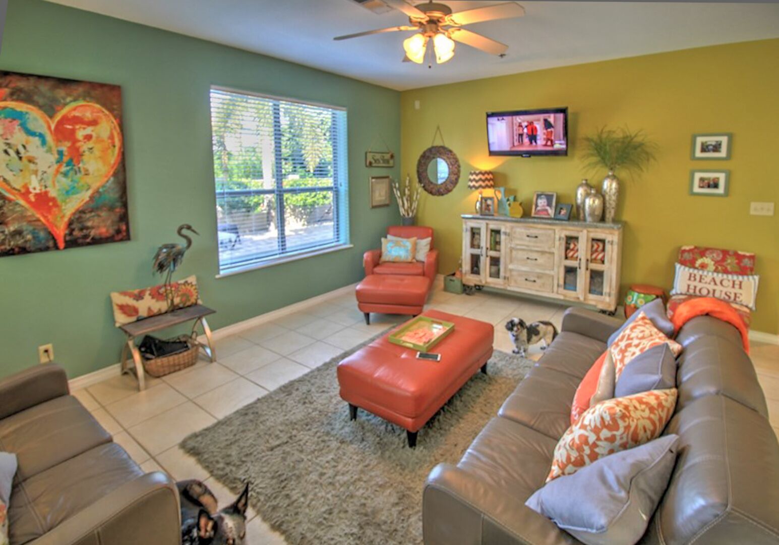 A living room with a sofa, ottoman, and a television.