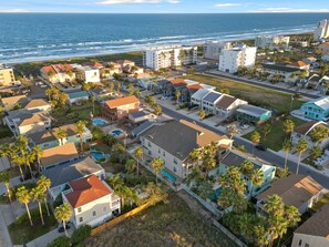 Vista aérea de una zona residencial costera con casas, una playa y el océano al fondo.