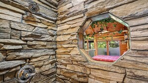 A stone-walled room with a window overlooking a wooden interior.