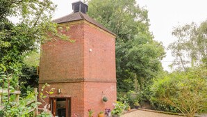 A brick building with a small door and window, surrounded by gravel and potted plants. - The Hyde Dovecote Kinver, pet Friendly Holiday let (Stourbridge)