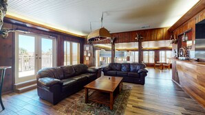 Ein geräumiges Wohnzimmer mit Ledersofas, einem Holztisch und einem großen Fernseher.