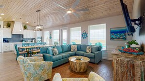 A spacious living area with a large sectional sofa, a round coffee table, and a dining area with a wooden table and chairs.