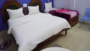 Un dormitorio con una cama grande, una cama más pequeña y una silla.